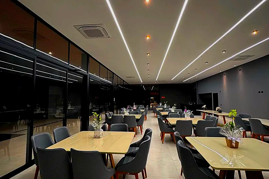 Salão de festas do clube do Infinitus, com mesas postas e iluminação linear